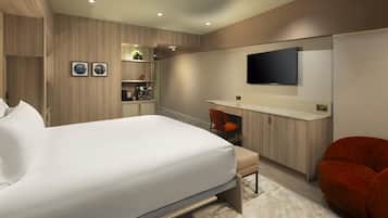 Ein modernes Hotelzimmer mit einem Bett, einem Schreibtisch, einem Stuhl und einem an der Wand befestigten Fernseher.