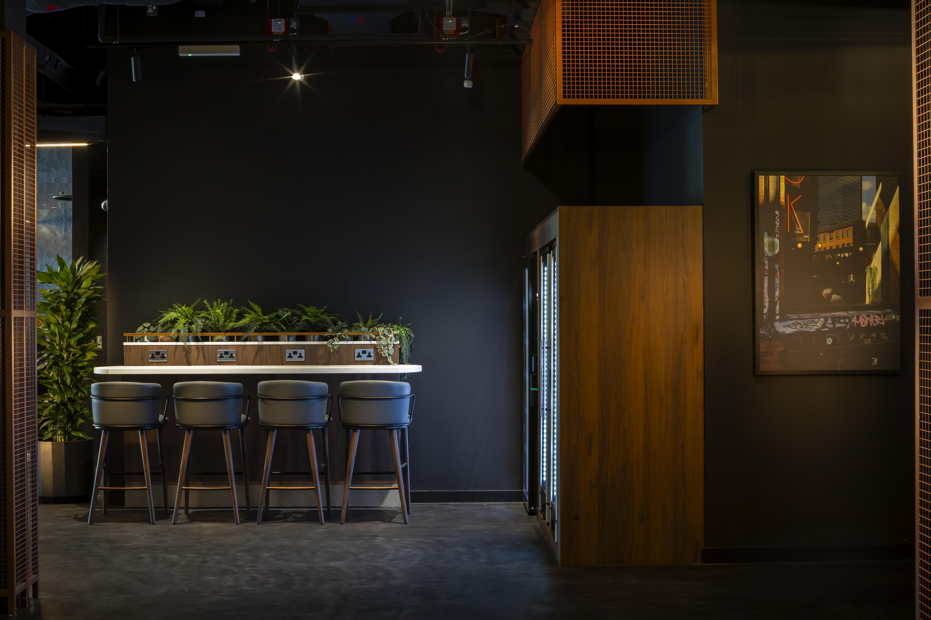 Een bargedeelte met een donkere muur, houten details en een plantenplank.