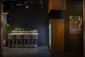 A bar area with a dark wall, wooden accents, and a plant shelf. - Radisson Blu Medlock Hotel, Manchester (Manchester)
