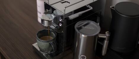 Una cafetera con jarra de vidrio y recipiente metálico sobre una superficie de madera.