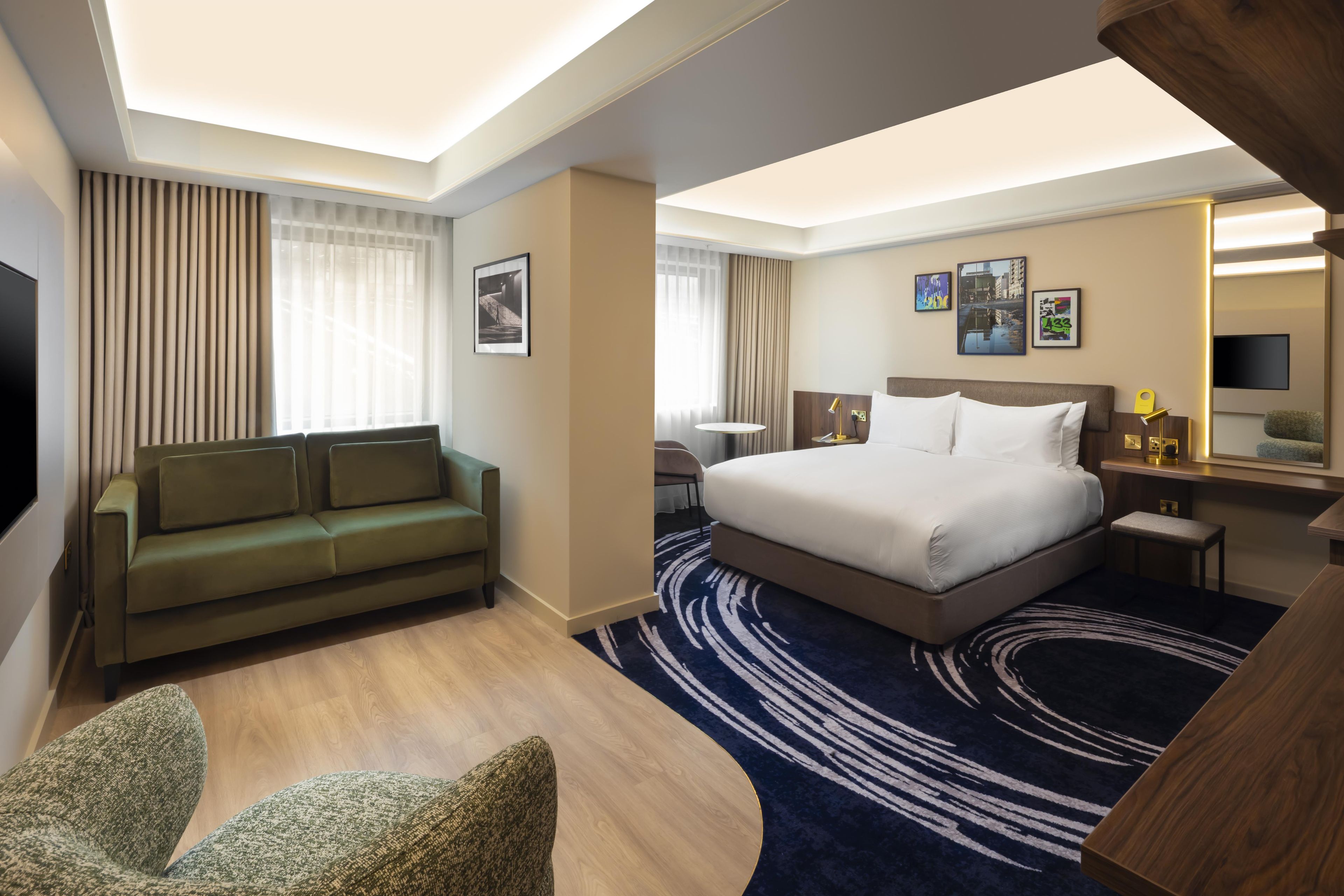Ein Hotelzimmer mit einem Bett, einer Couch, einem Schreibtisch und einem Fernseher.