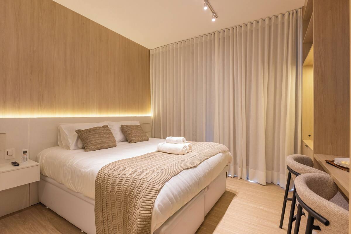 Une chambre d’hôtel moderne avec un grand lit, une table de chevet avec un téléphone et un bureau avec une chaise.