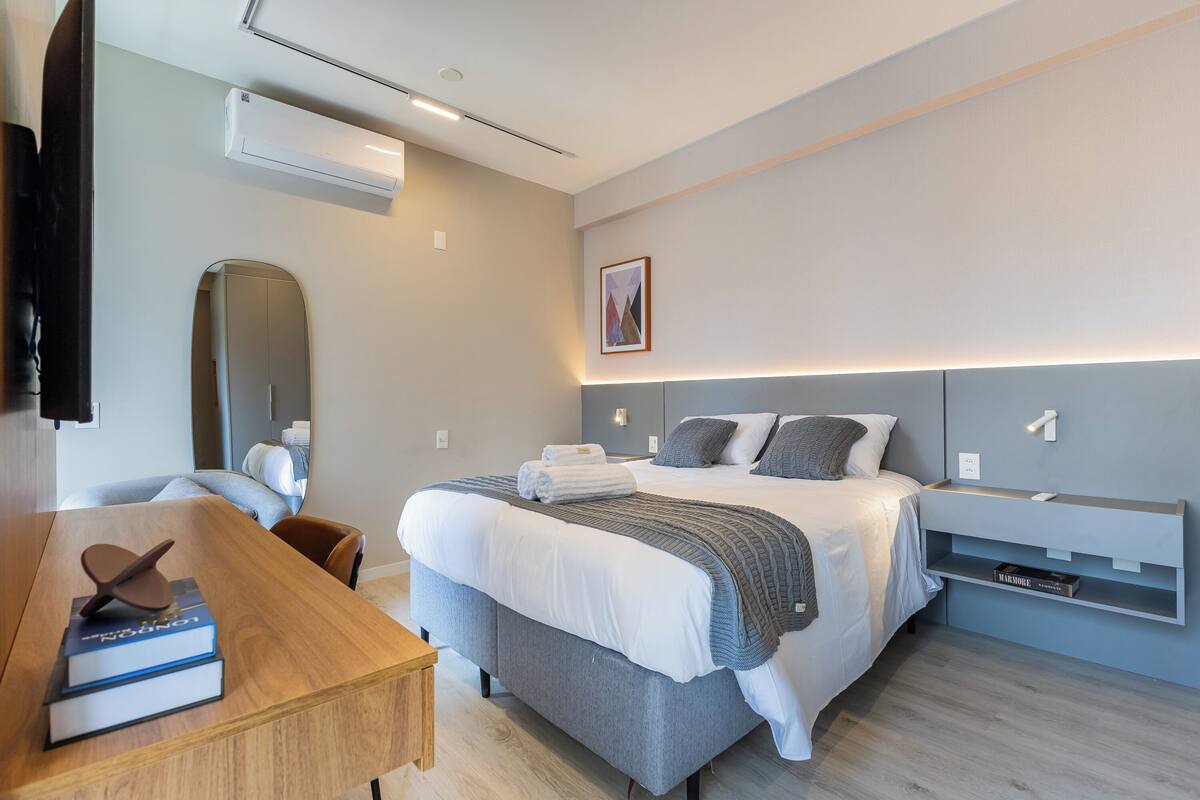 Une chambre d’hôtel moderne équipée d’un lit, de tables de chevet, d’un bureau et d’un téléviseur à écran plat.