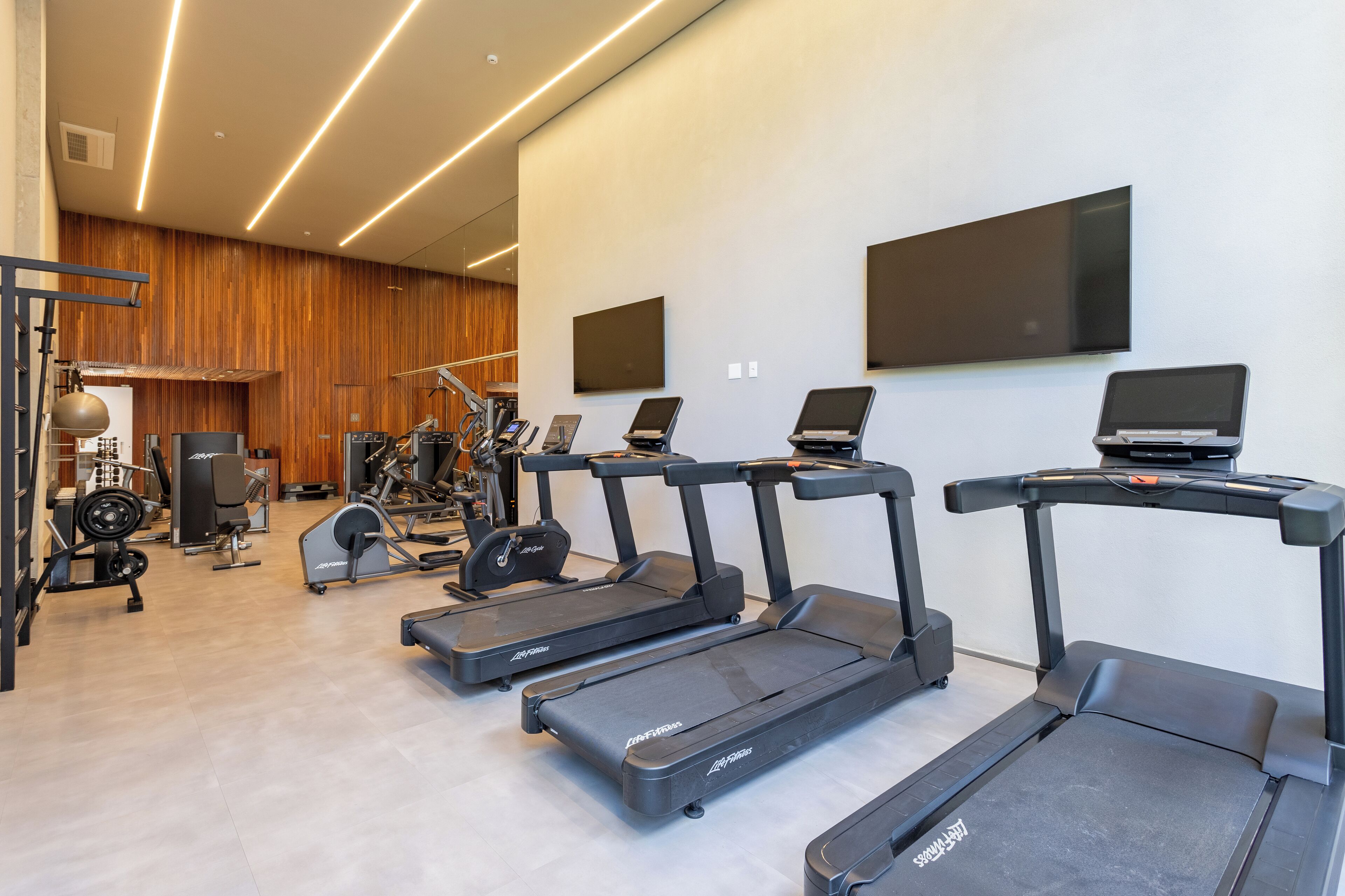 A modern gym with treadmills, weight machines, and a mirror wall.
