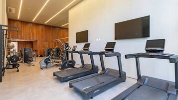 A modern gym with treadmills, weight machines, and a mirror wall.
