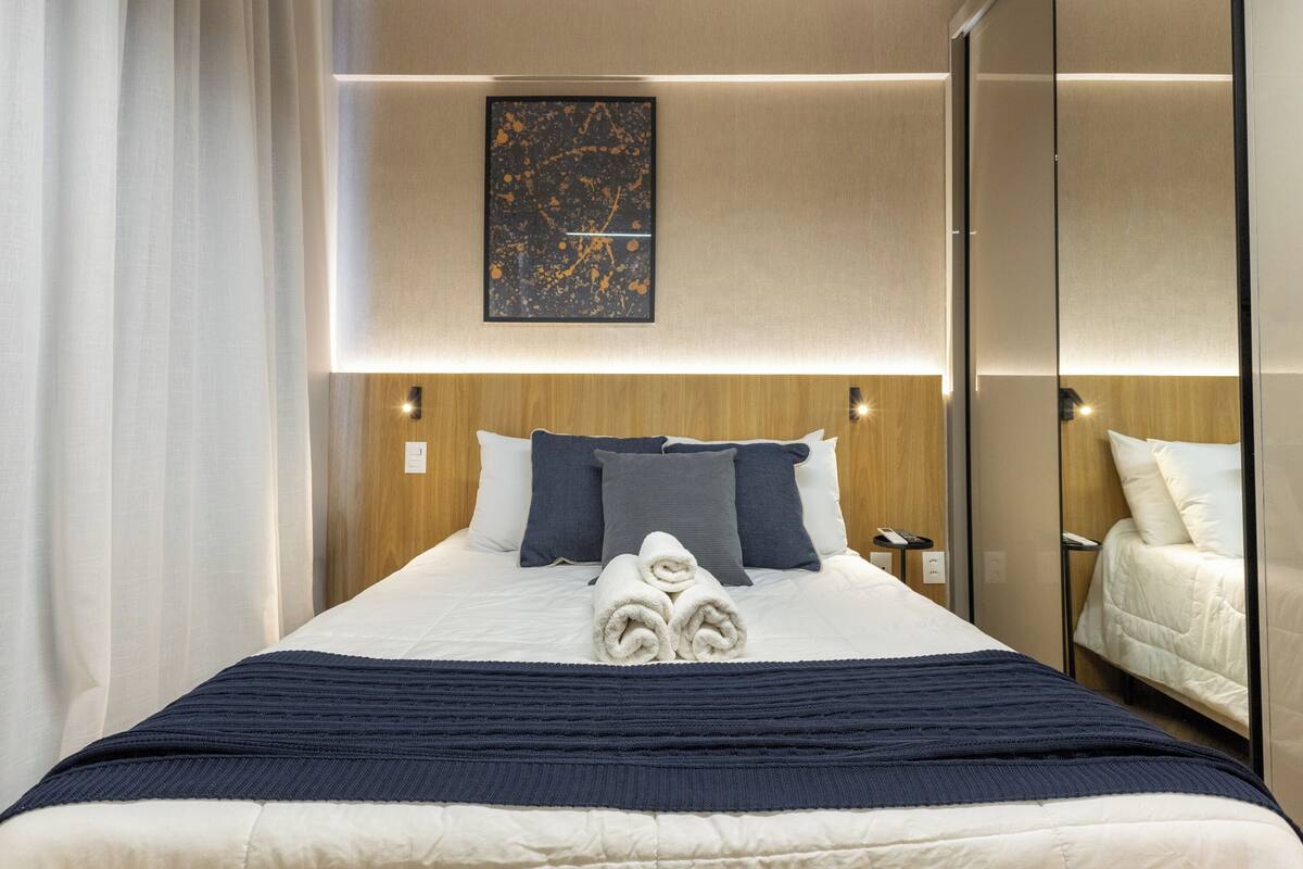 Une chambre d’hôtel avec un lit bien fait, une table de chevet, une œuvre d’art accrochée au mur et un miroir.