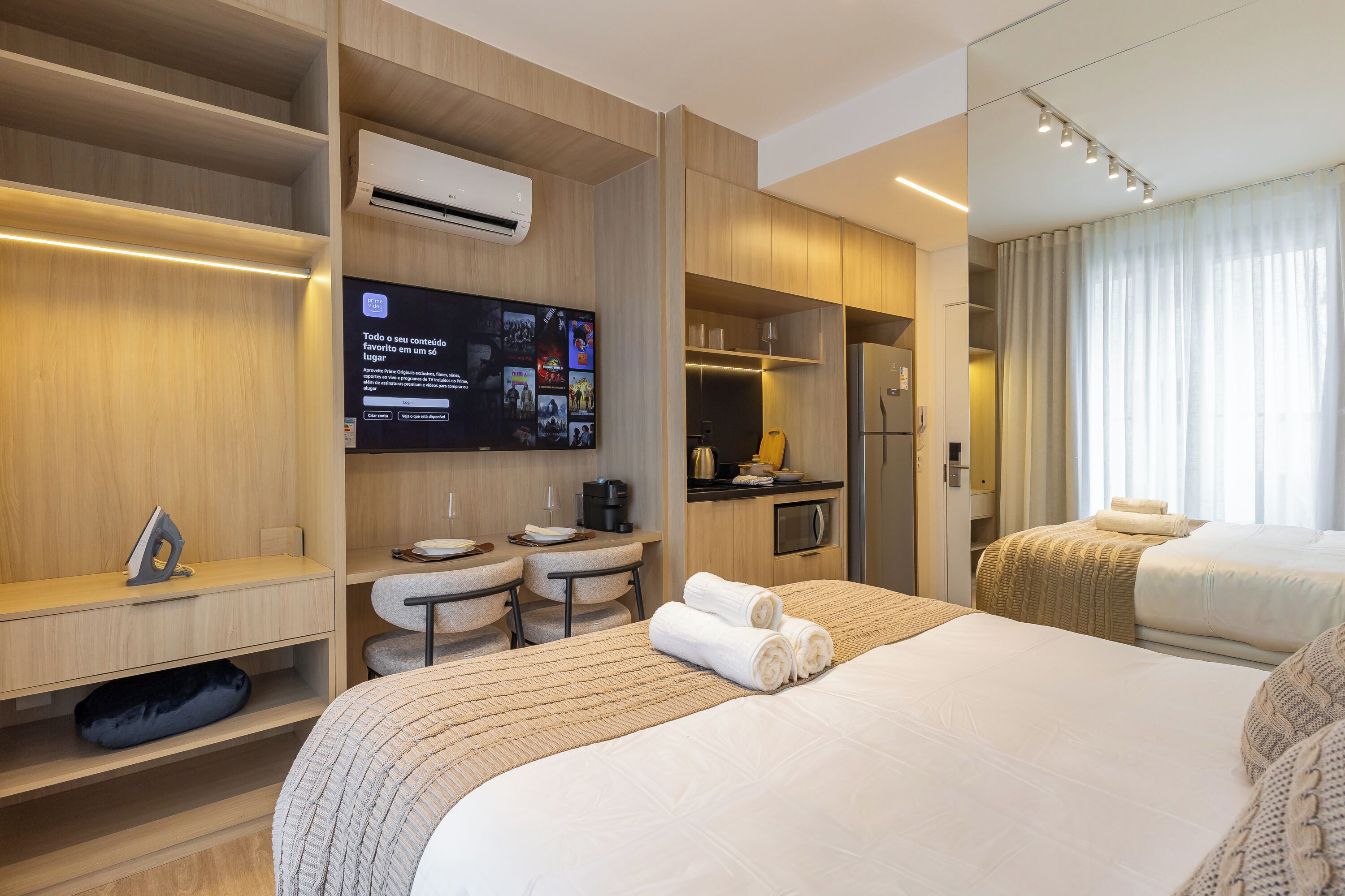 Una camera d'albergo con un letto, una scrivania, una sedia, una TV e angolo cottura.