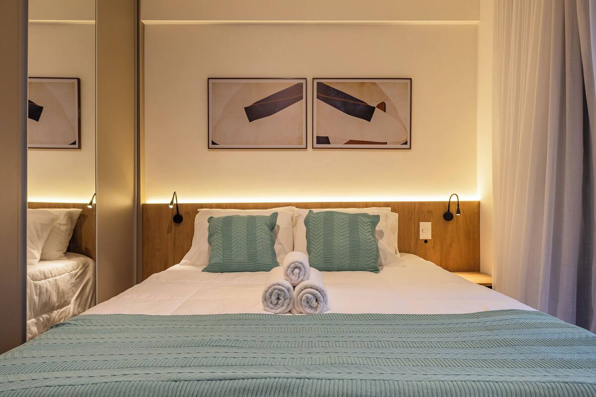 Une chambre d’hôtel comprenant un lit, deux oreillers, une couverture et deux œuvres d’art accrochées au mur.