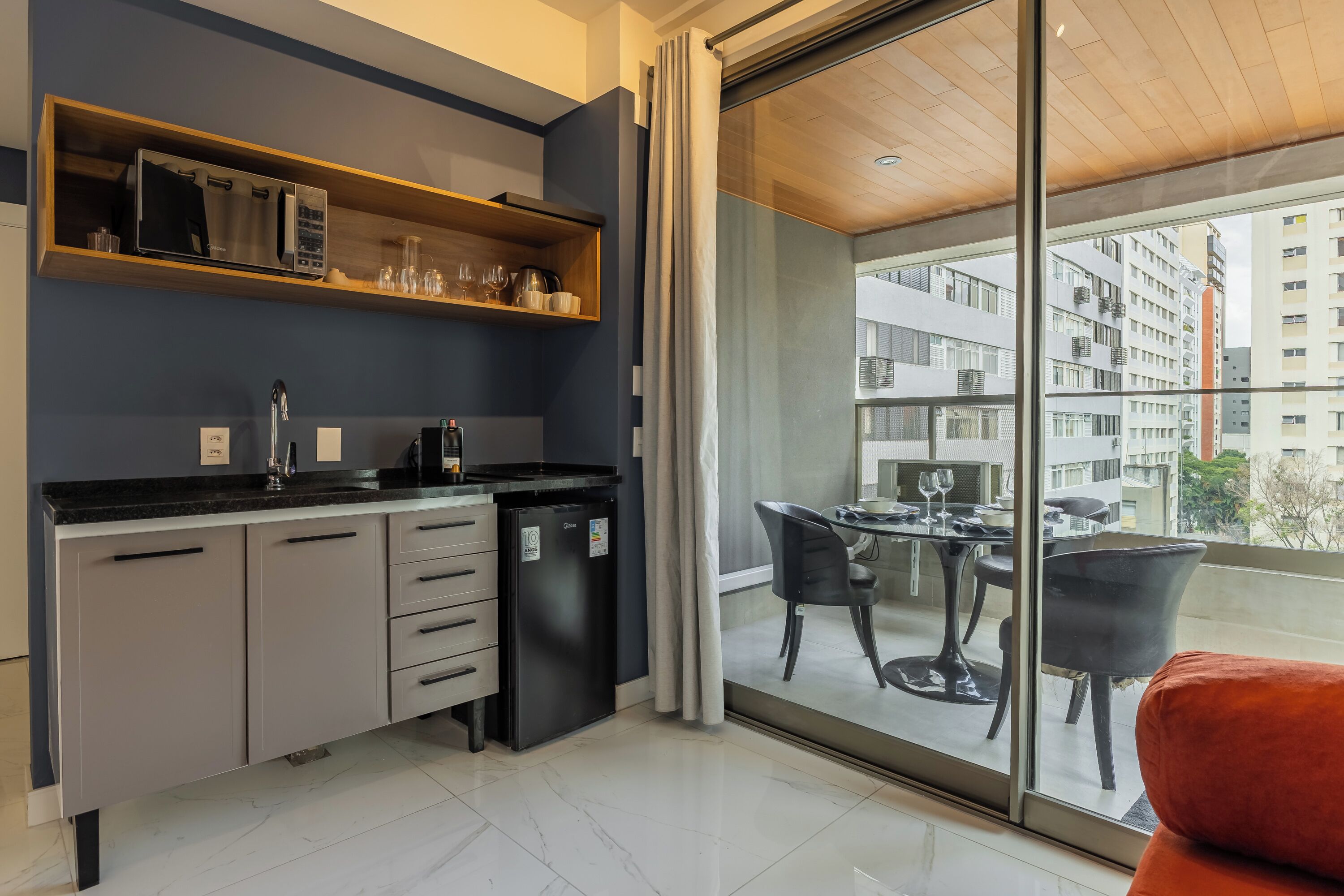 A modern kitchen with a built-in microwave, a refrigerator, and a dining area with a table and chairs.