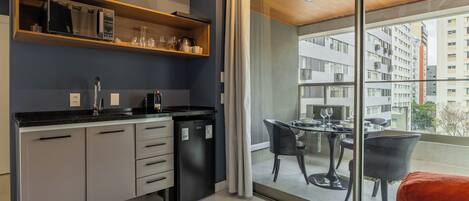 A modern kitchen with a built-in microwave, a refrigerator, and a dining area with a table and chairs.