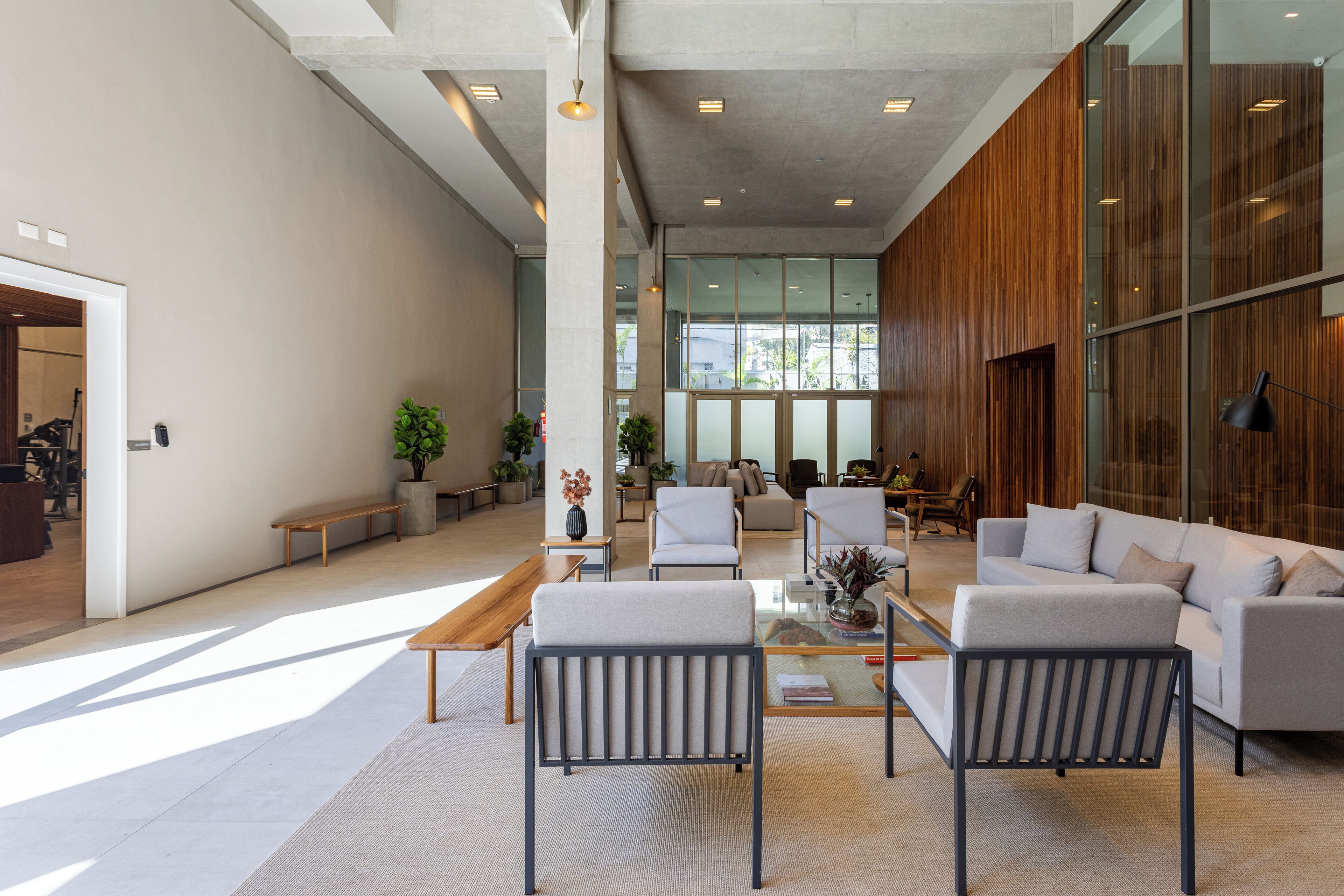 A spacious lobby with a modern design, featuring a seating area with sofas and chairs, a coffee table, and a large window providing natural light.