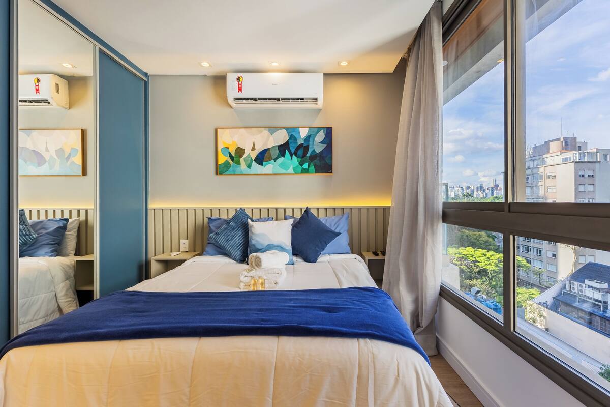 Une chambre d’hôtel avec un grand lit, une vue sur la ville et la climatisation.