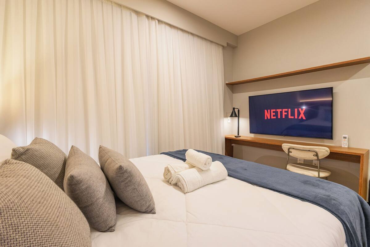 Une chambre d’hôtel avec un lit, des oreillers, une télévision et un bureau.