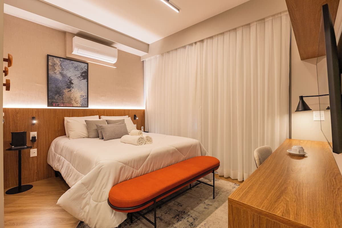 Une chambre d’hôtel avec un lit, une banquette, un bureau et un tableau au mur.