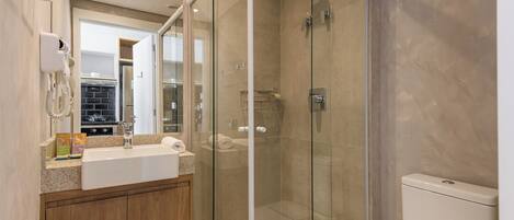 A modern bathroom with a glass-enclosed shower, a sink with a countertop, and a toilet.