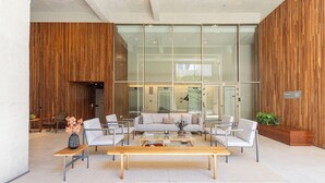 Un hall d’entrée moderne doté d’un grand mur de verre, d’un comptoir de réception et d’un espace salon avec une table basse.
