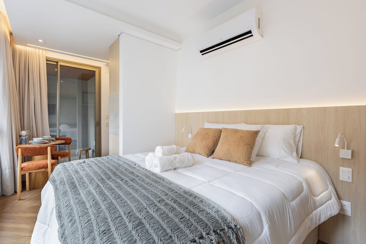Une chambre d’hôtel comprenant un lit, un bureau avec une chaise et une porte vitrée donnant sur un balcon.
