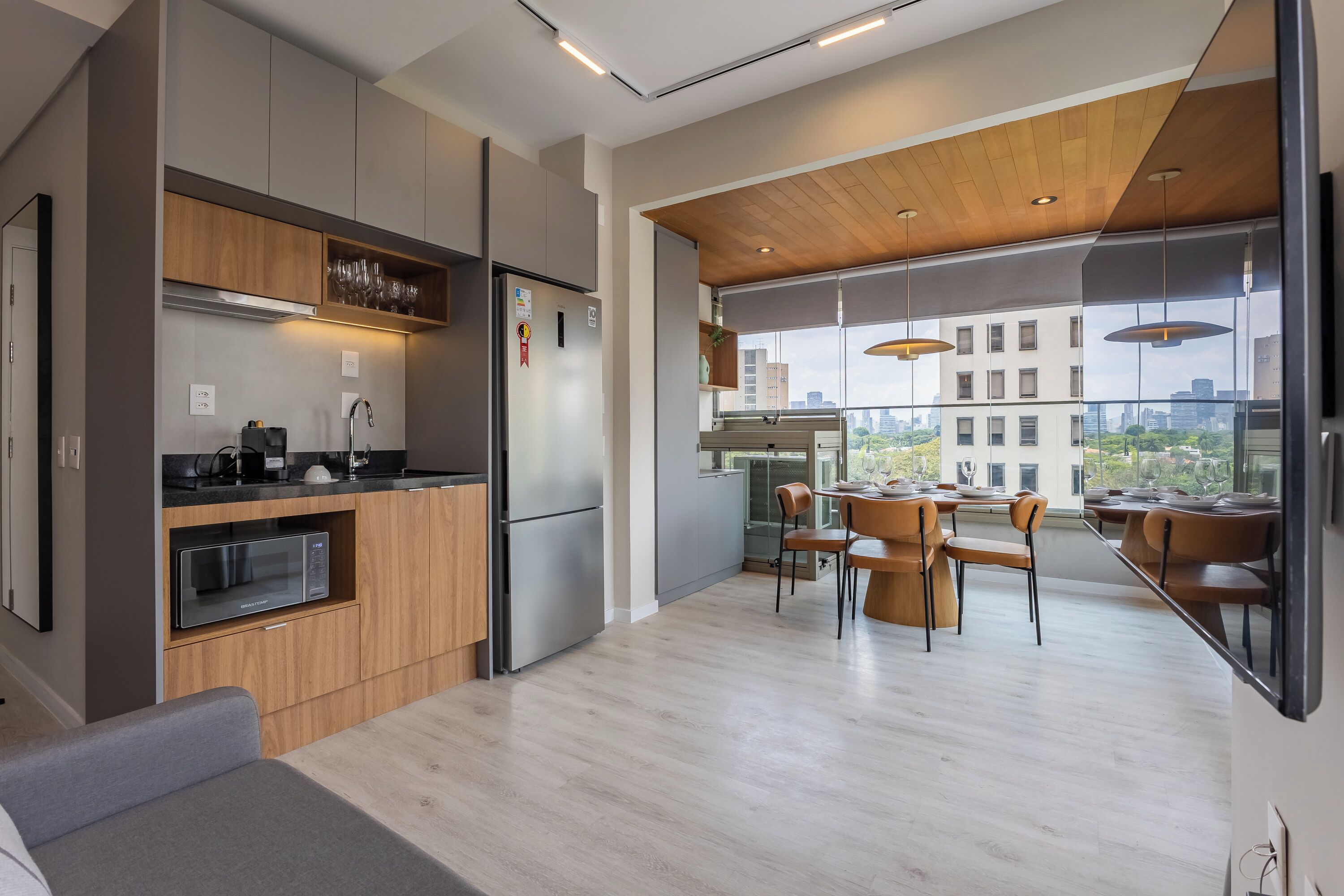 A modern kitchen with wooden cabinets, a built-in microwave, and a dining area with a large table and chairs.