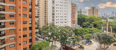A multi-story building with a brick facade, surrounded by greenery and construction equipment.