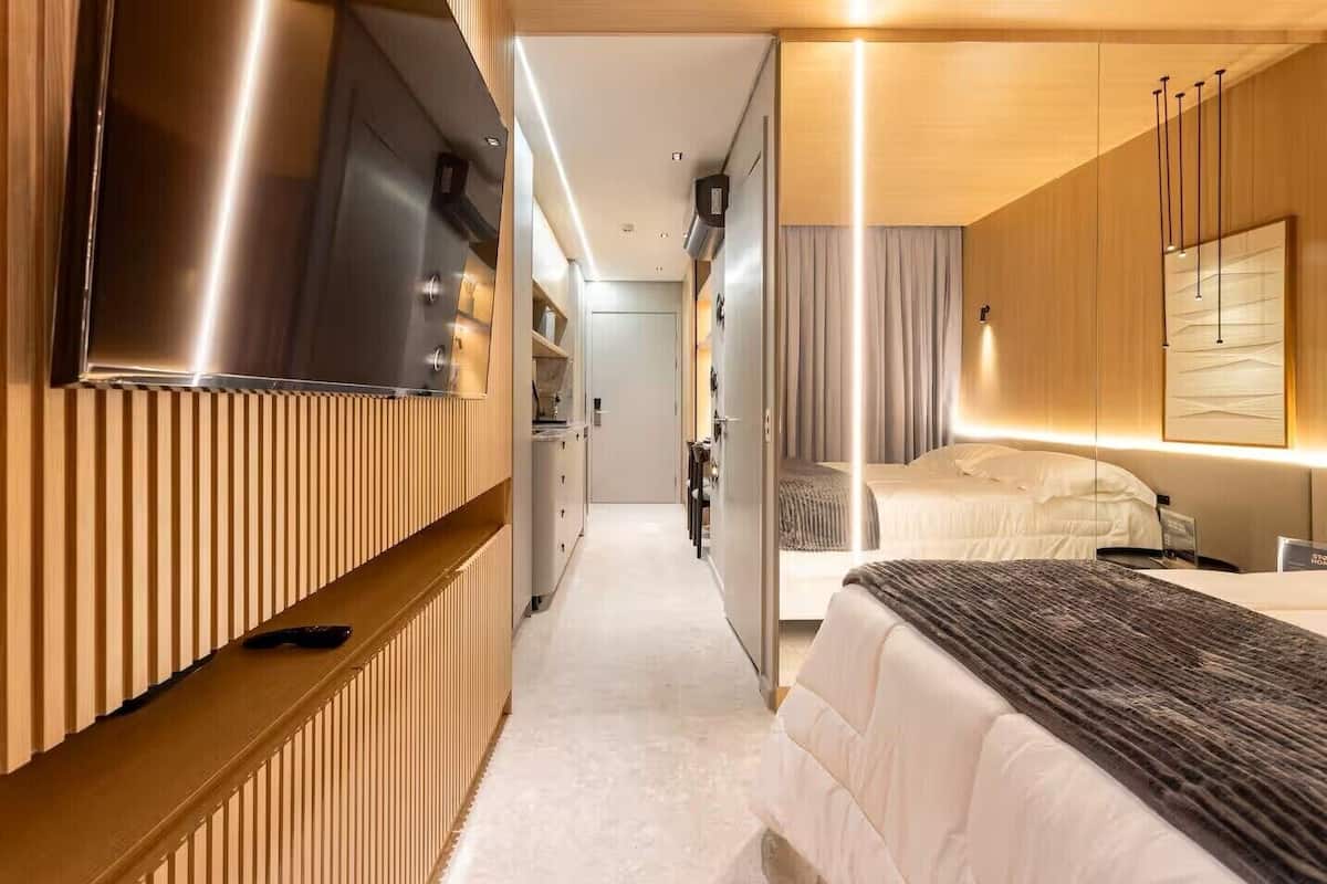 Une chambre d’hôtel moderne dotée d’un grand lit, d’un téléviseur fixé au mur et d’un coin cuisine.