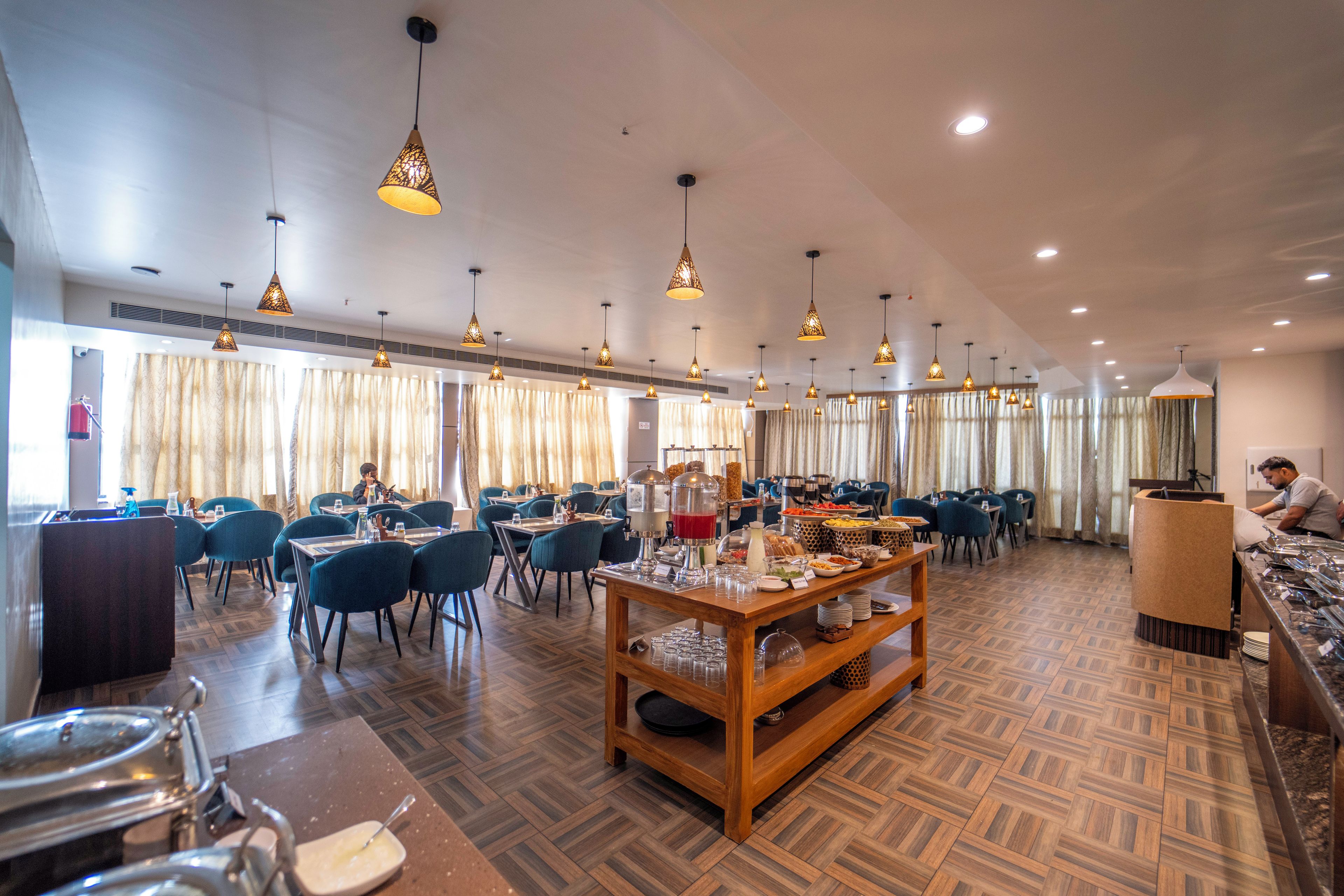 Un grand espace dédié à la salle à manger, avec plusieurs tables et chaises, un éclairage au plafond et un buffet.