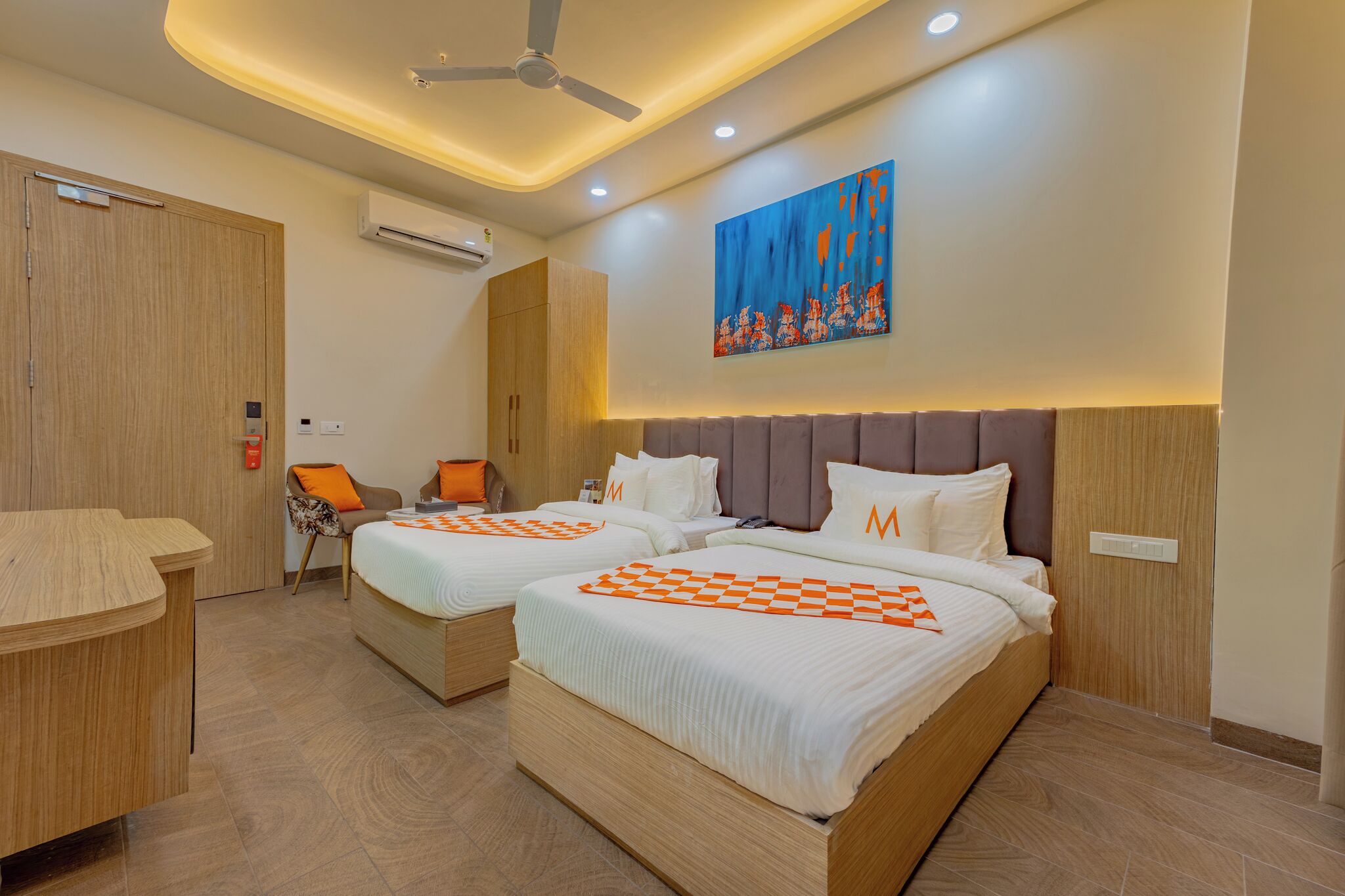 Habitación de hotel con dos camas, un escritorio, un equipo de aire acondicionado y un ventilador de techo.