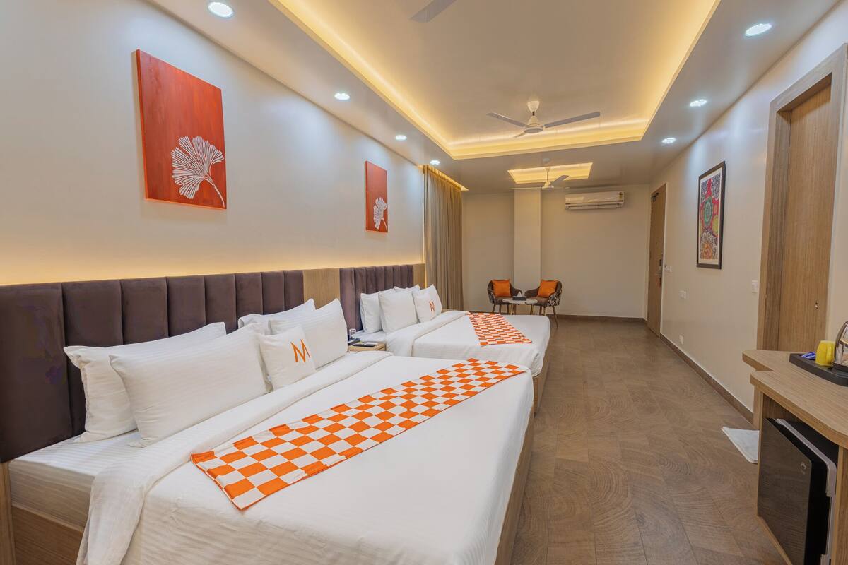 A hotel room with three beds, a dining area, and a ceiling fan.