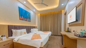 A hotel room with two beds, a desk, a TV, and a ceiling fan. - Mosaic Connect Ayodhya (Faizabad)