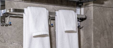 A bathroom with a towel rack holding three white towels.