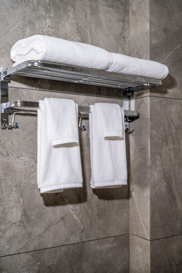 A bathroom with a towel rack holding three white towels. - Mosaic Connect Ayodhya (Faizabad)