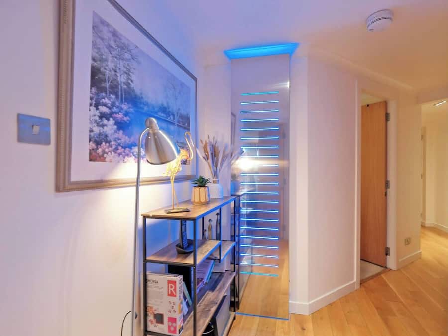 Un couloir doté d’un luminaire moderne, d’un tableau encadré et d’un plancher en bois.