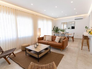 Una sala de estar moderna con sofá, mesa de centro y un comedor con sillas y mesa.