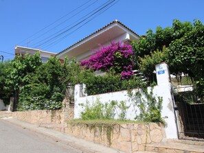 A residential building with a stone wall, a metal gate, and a clear blue sky. - Apartment for 4 by the beach with AC and parking (Llançà)