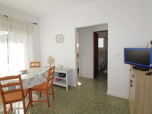 A room with a dining table, chairs, a television, and a door leading to a bathroom. - Apartment for 4 by the beach with AC and parking (Llançà)