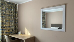 Een kamer met een bureau, stoel en een spiegel aan de muur.