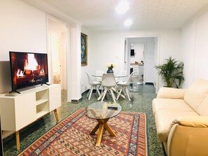 A living room with a TV, a sofa, a dining table with chairs, and a kitchen in the background. - Spacious apartment with terrace - Near Málaga city center (Málaga)