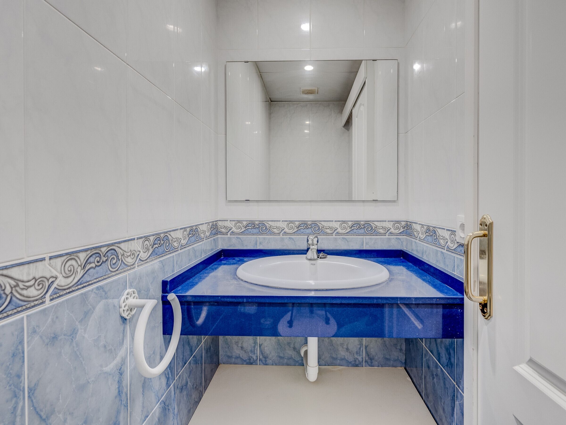 Une salle de bain avec un lavabo blanc, des carreaux de marbre bleus et un miroir au-dessus du lavabo.