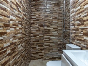 A shower with a stone mosaic wall, a toilet, and a bathtub. - Modern and functional apartment in Malaga, near beaches (Málaga)