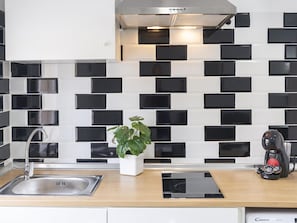 A modern kitchen with a black and white tiled backsplash, stainless steel appliances, and a potted plant. - Modern and functional apartment in Malaga, near beaches (Málaga)