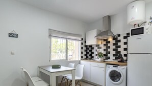 Ett modernt kök med en inbyggd tvättmaskin, en matplats med bord och stolar samt ett fönster med persienner.