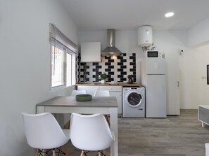 A compact kitchen with a washing machine, a refrigerator, and a tiled backsplash. - Modern and functional apartment in Malaga, near beaches (Málaga)