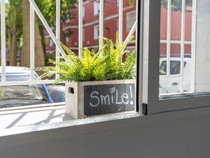A window with a potted plant and a sign that says 'Smile!' - Modern and functional apartment in Malaga, near beaches (Málaga)