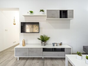A modern living room with a white console table, grey cabinets, a mounted TV, and decorative plants. - Modern and functional apartment in Malaga, near beaches (Málaga)