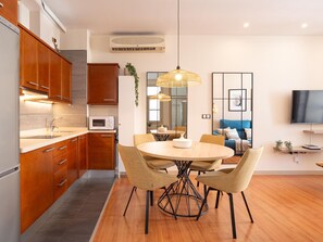 Una cocina moderna con armarios de madera, microondas y un comedor con mesa y sillas redondas.