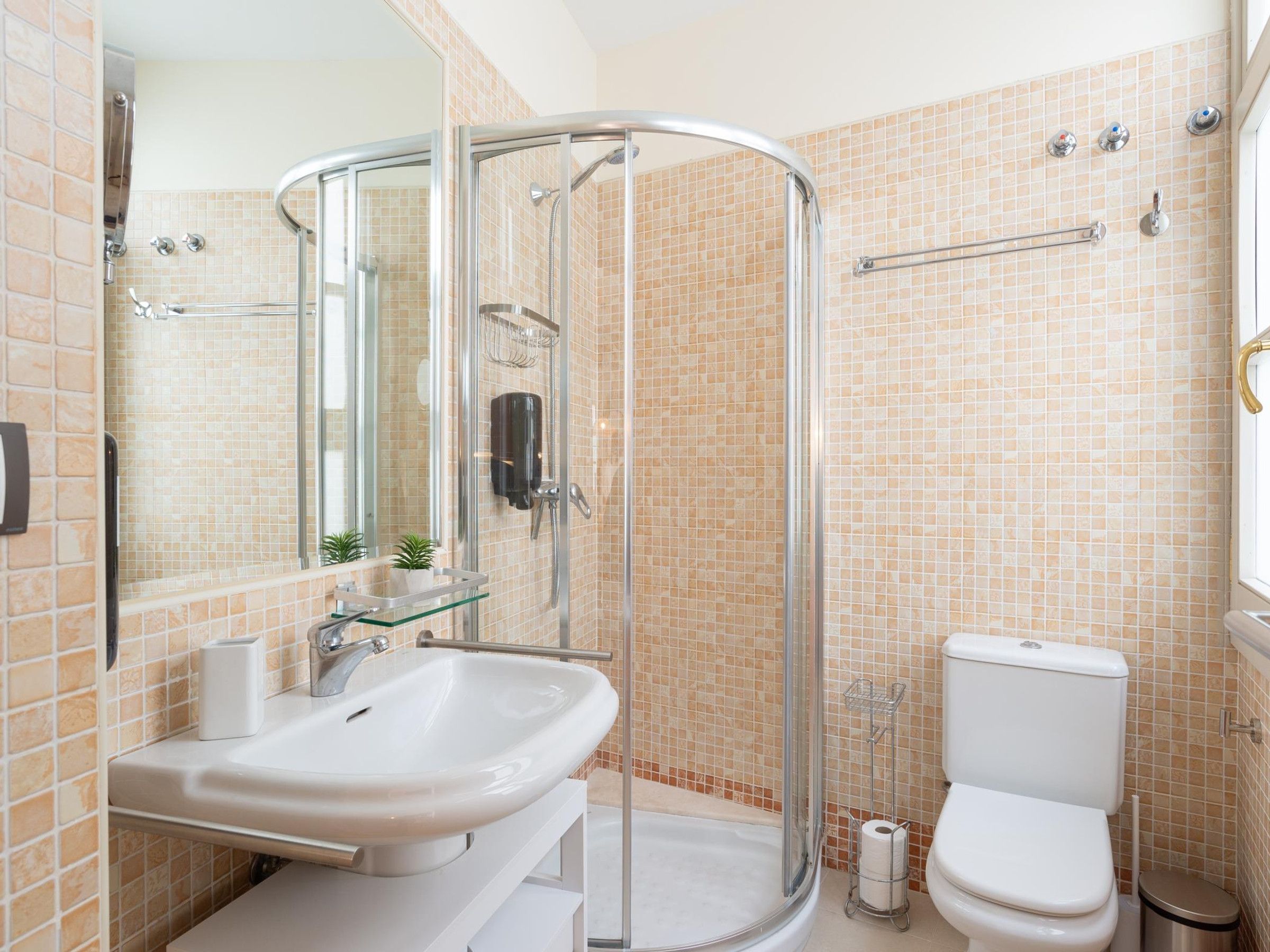 A bathroom with a glass-enclosed shower, a sink, a toilet, and a mirror.