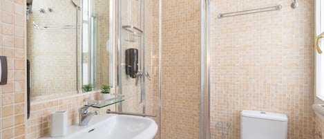 A bathroom with a glass-enclosed shower, a sink, a toilet, and a mirror.