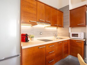 A modern kitchen with wooden cabinets, a stainless steel sink, a red coffee machine, a microwave, and a potted plant. - Bright apartment in the heart of Malaga, ideal for long stays (Málaga)