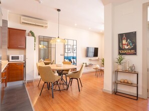 Un espacio habitable moderno con comedor, cocina y televisor montado en la pared.