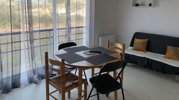 Ein Zimmer mit Esstisch, Stühlen, einer Couch und Blick ins Freie.