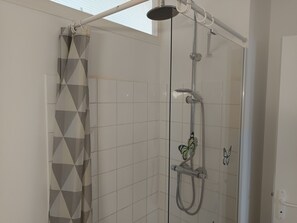 A shower area with a glass door, a showerhead, and a butterfly decoration. - Bohemian Apartment Near Beach - Pets Welcome - Private Parking (Notre-Dame-de-Monts)